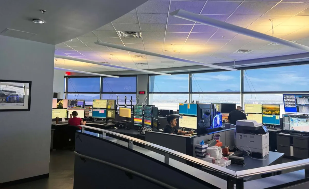 Operators at workstations in a control room glazed along one wall