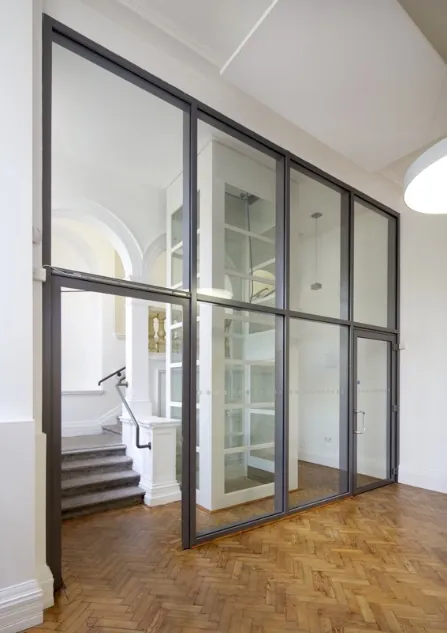 Slim framed glazed partition and door beside a period staircase